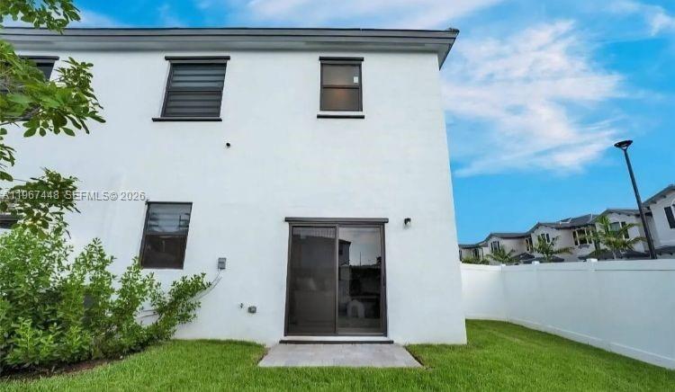 The exterior of a white two-story townhouse features a sliding glass door and lawn — 20366 NW 4th Path, Miami Gardens FL 33169, MIAMI GARDENS, FL