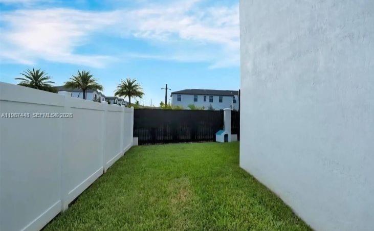 A grassy side yard is enclosed by a white vinyl fence and a black metal fence — 20366 NW 4th Path, Miami Gardens FL 33169, MIAMI GARDENS, FL