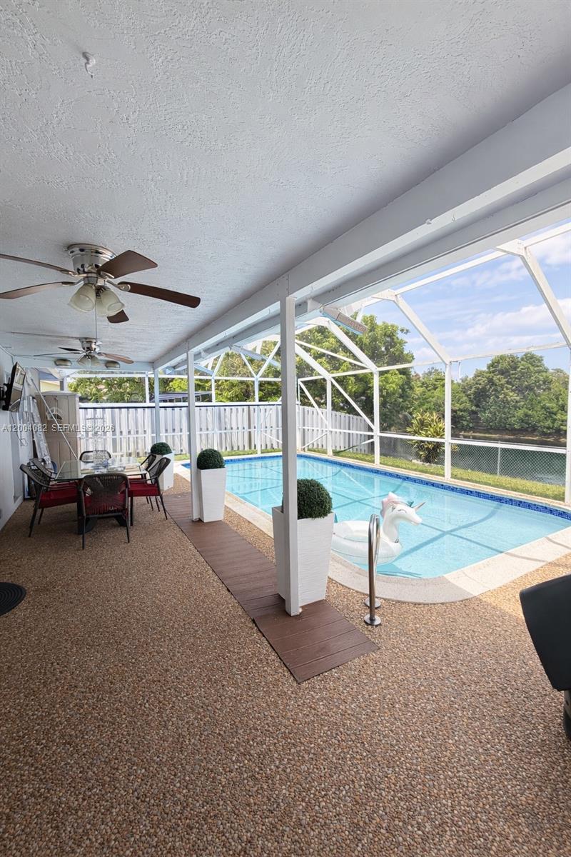 A covered patio features a dining set, ceiling fans, and a pool with a screen enclosure — 8085 NW 21st St, Sunrise FL 33322, SUNRISE, FL
