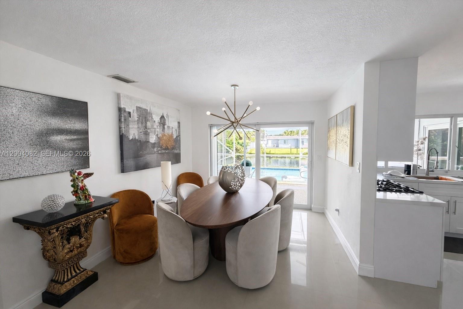 A dining room features an oval wooden table, modern chairs, and a gold sputnik chandelier — 8085 NW 21st St, Sunrise FL 33322, SUNRISE, FL