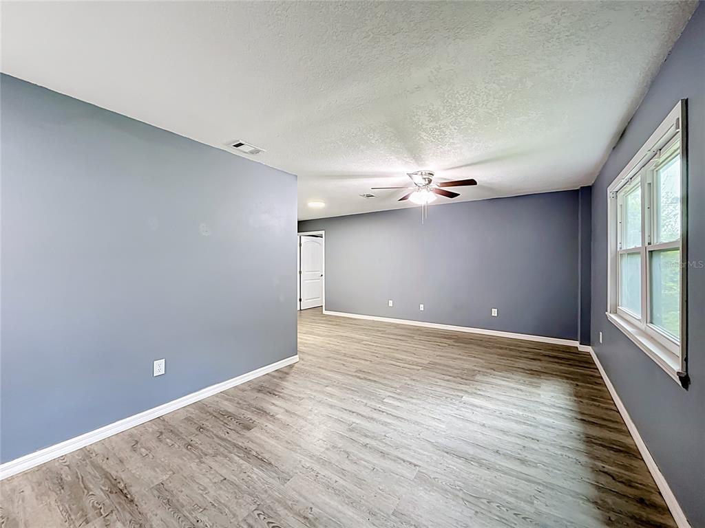 An empty room with gray walls, wood-look flooring, a ceiling fan, and a window — 1218 CR 450, LAKE PANASOFFKEE, FL