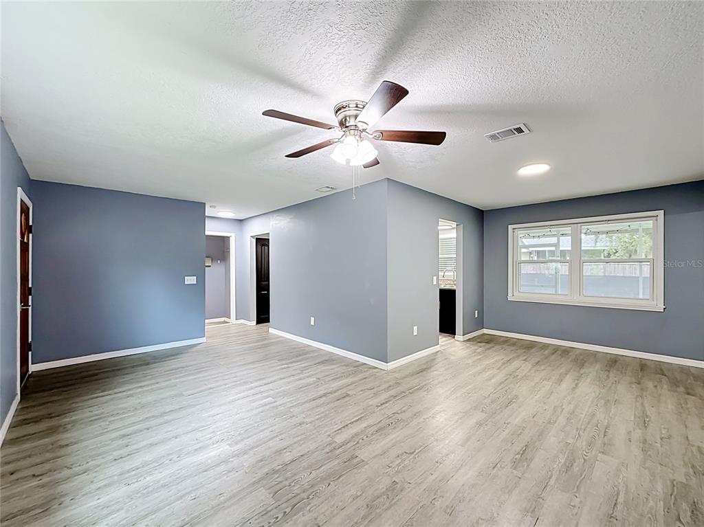 A living room with light gray walls, wood-look flooring, a ceiling fan, and a window — 1218 CR 450, LAKE PANASOFFKEE, FL