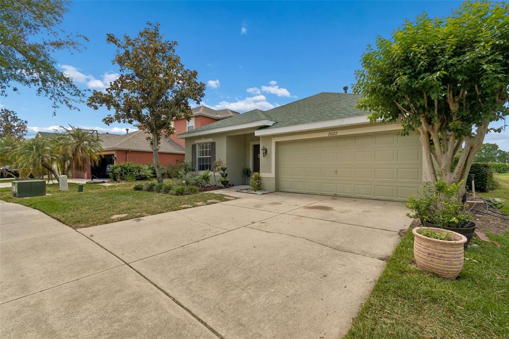 A single-story house with a green exterior, a two-car garage, and a concrete driveway — 20122 NOB OAK AVENUE, TAMPA, FL