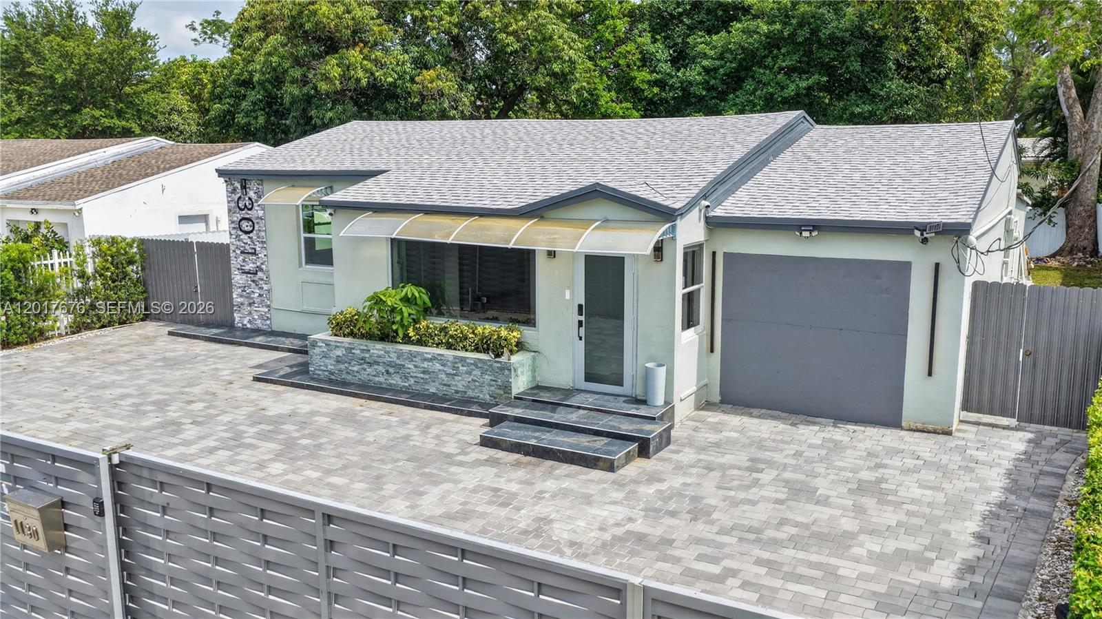 A single-story house with a paved driveway, a stone planter, and a gray garage door — 1130 NW 57th St, Miami FL 33127, MIAMI, FL