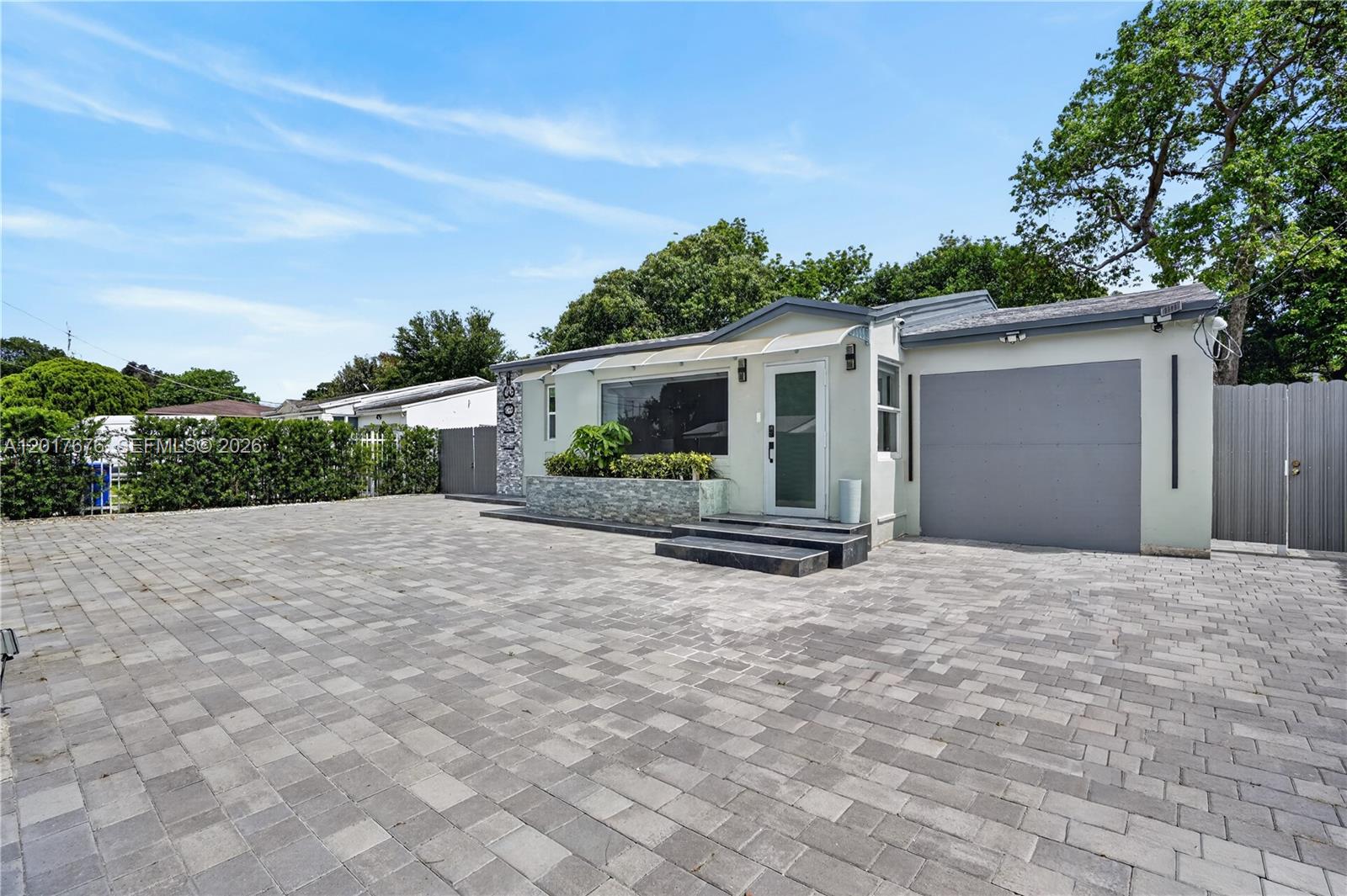 A single-story house with a paved driveway, a gray garage door, and a front entrance — 1130 NW 57th St, Miami FL 33127, MIAMI, FL