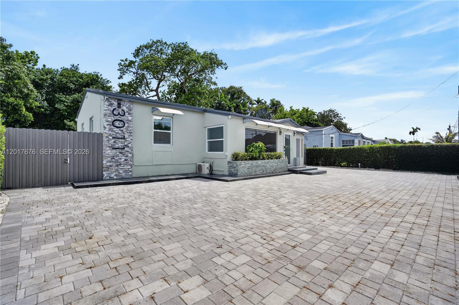 A light-colored house features a stone-accented facade and a large paved driveway — 1130 NW 57th St, Miami FL 33127, MIAMI, FL