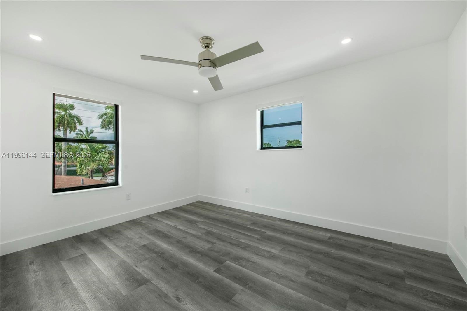 A bedroom features white walls, gray wood-look flooring, a ceiling fan, and two windows — 10370 SW 24th St # B, Miami FL 33165, MIAMI, FL