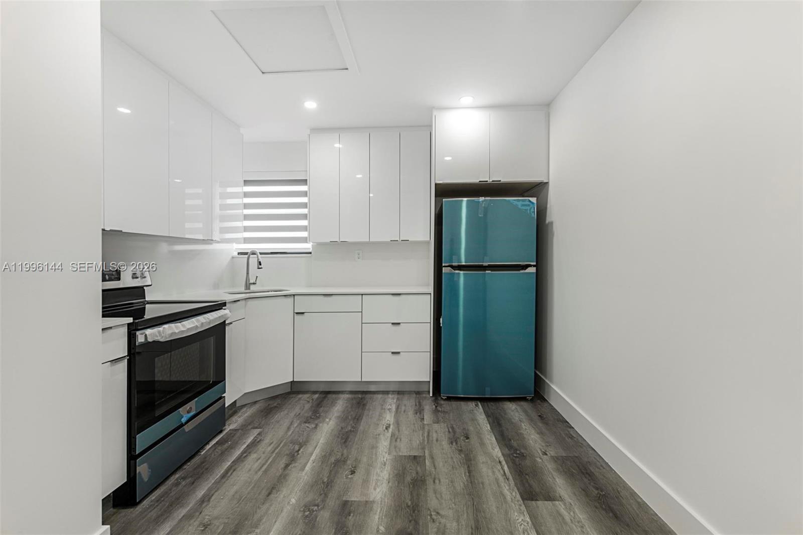 A modern kitchen features white cabinets, stainless steel appliances, and wood-look flooring — 10370 SW 24th St # B, Miami FL 33165, MIAMI, FL