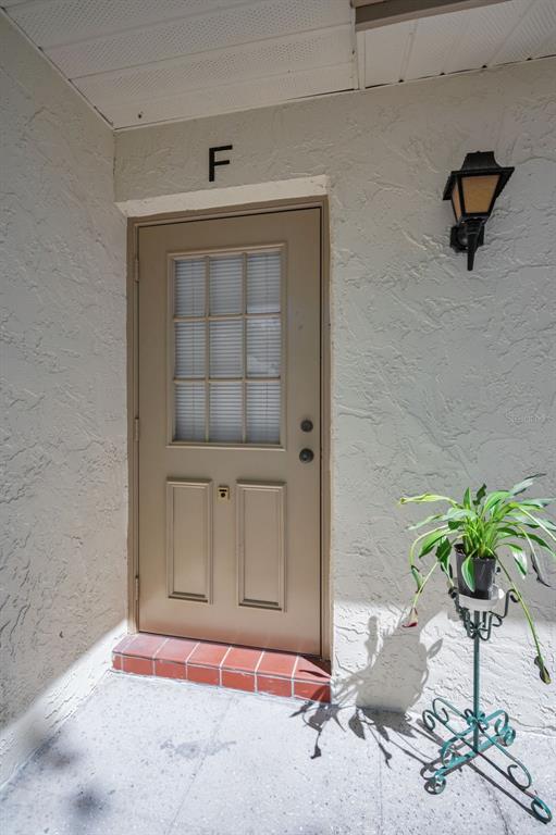 A tan exterior door marked with the letter F features a window and red-tiled step — 1333 SHADY PINE WAY UNIT F, TARPON SPRINGS, FL