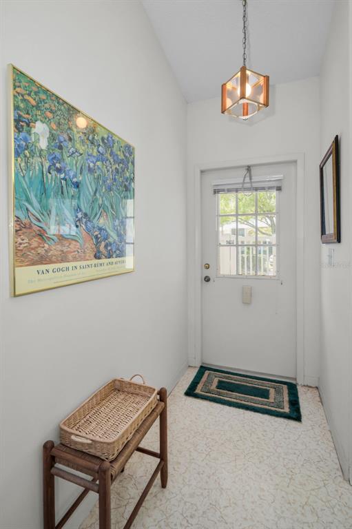 An entryway features a white door, a Van Gogh print, a wooden table, and pendant lighting — 1333 SHADY PINE WAY UNIT F, TARPON SPRINGS, FL