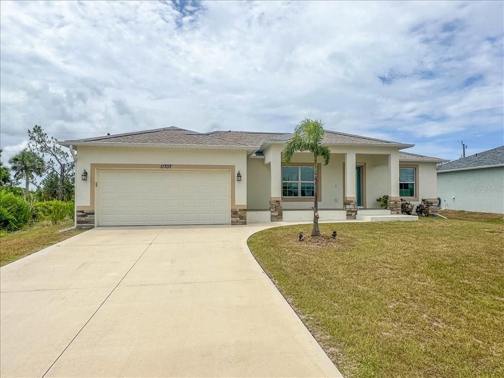 A single-story house with a two-car garage, stone accents, and a palm tree out front — 11707 WILLMINGTON BOULEVARD, PORT CHARLOTTE, FL
