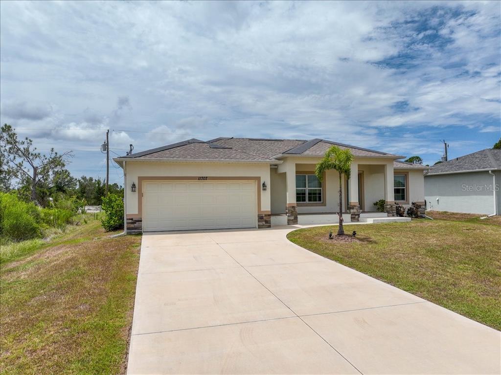 A single-story house with a beige exterior, a two-car garage, and a concrete driveway — 11707 WILLMINGTON BOULEVARD, PORT CHARLOTTE, FL