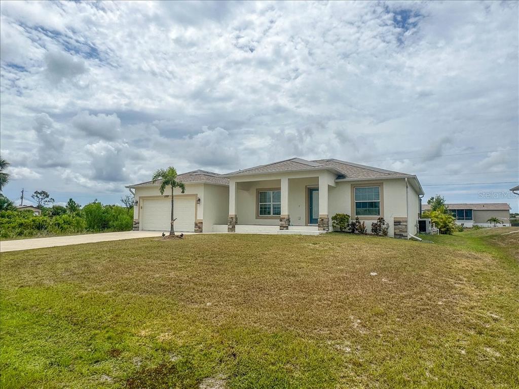 A single-story house with a beige stucco exterior, stone accents, and a two-car garage — 11707 WILLMINGTON BOULEVARD, PORT CHARLOTTE, FL