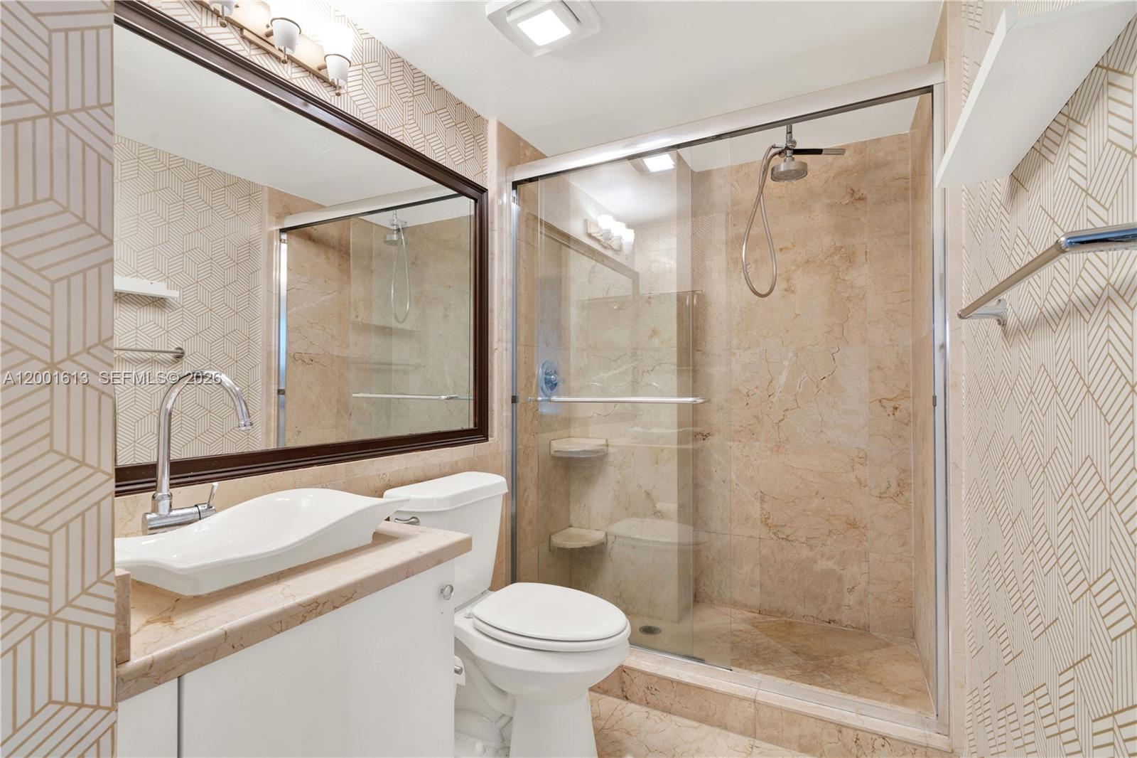 A bathroom features a vessel sink, a toilet, and a glass-enclosed shower with beige tiles — 5077 NW 7th St # 508, Miami FL 33126, MIAMI, FL