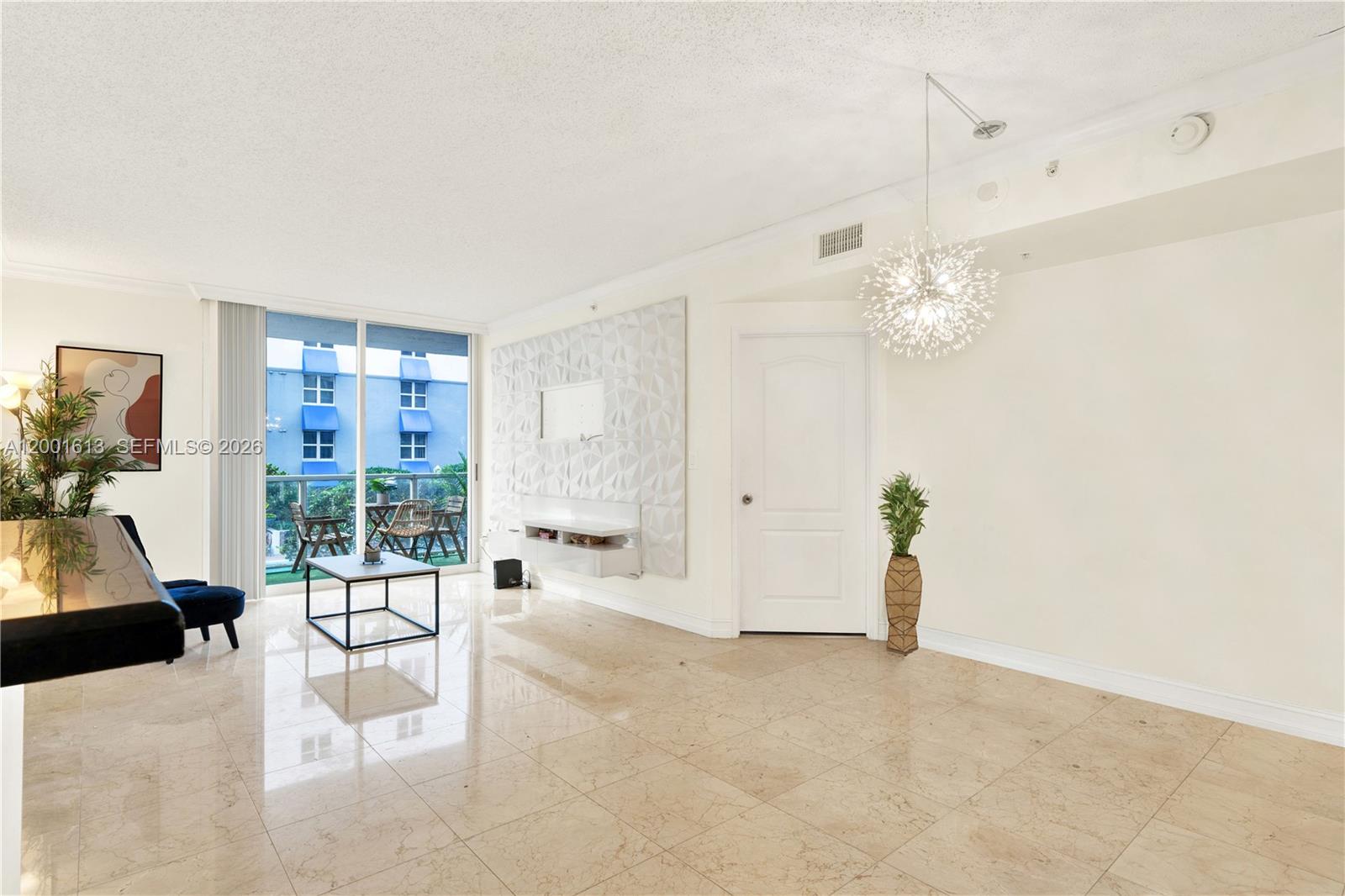 A living room features light tile floors, a textured accent wall, and a modern chandelier — 5077 NW 7th St # 508, Miami FL 33126, MIAMI, FL