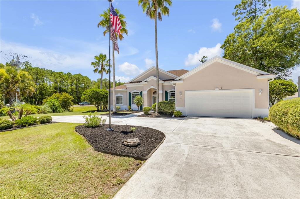 A single-story house with a beige exterior, a two-car garage, and a flag pole — 1 WELLINGTON DRIVE, PALM COAST, FL