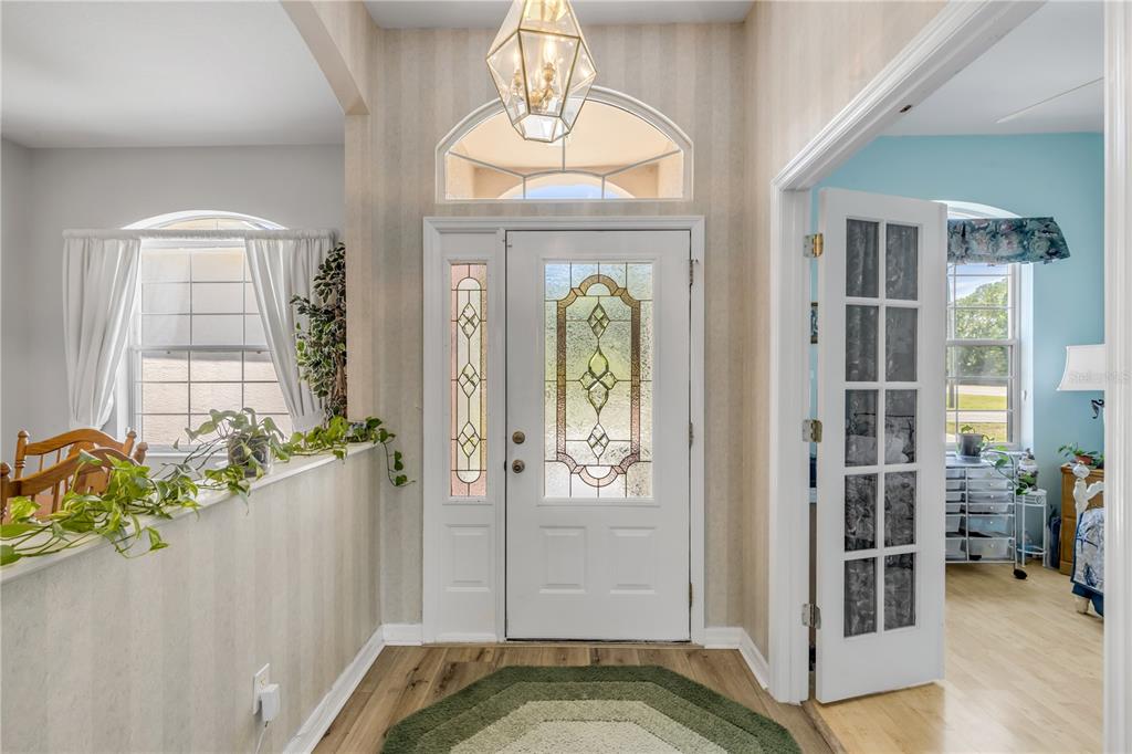An entryway features a white front door with decorative glass, a pendant light, and wood flooring — 1 WELLINGTON DRIVE, PALM COAST, FL
