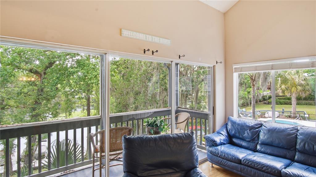 A sunroom with a blue leather sofa, wicker chairs, and large windows overlooking trees — 20800 RIVER DRIVE UNIT A31, DUNNELLON, FL