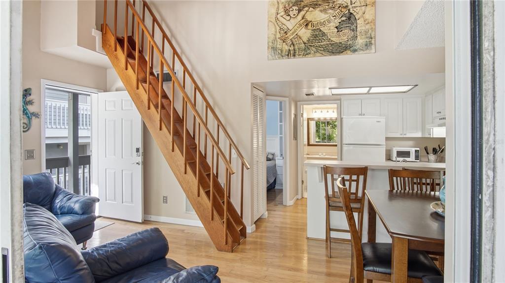 An interior view shows a living area with a wooden staircase, kitchen, and dining space — 20800 RIVER DRIVE UNIT A31, DUNNELLON, FL