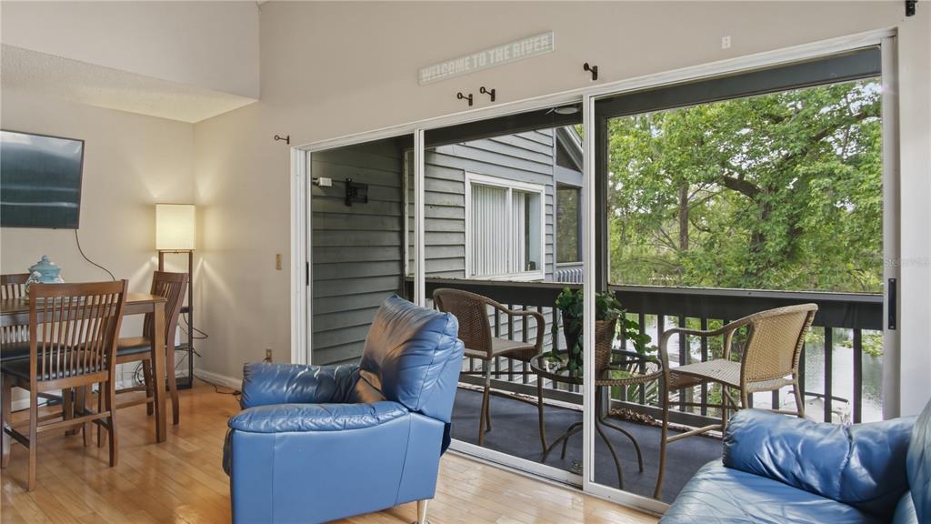 A living room with blue leather furniture and a sliding glass door opening to a balcony — 20800 RIVER DRIVE UNIT A31, DUNNELLON, FL