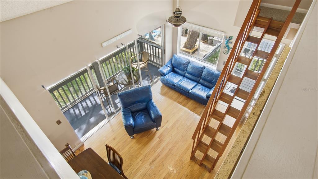A high-angle view of a living room with hardwood floors, blue furniture, and wooden stairs — 20800 RIVER DRIVE UNIT A31, DUNNELLON, FL