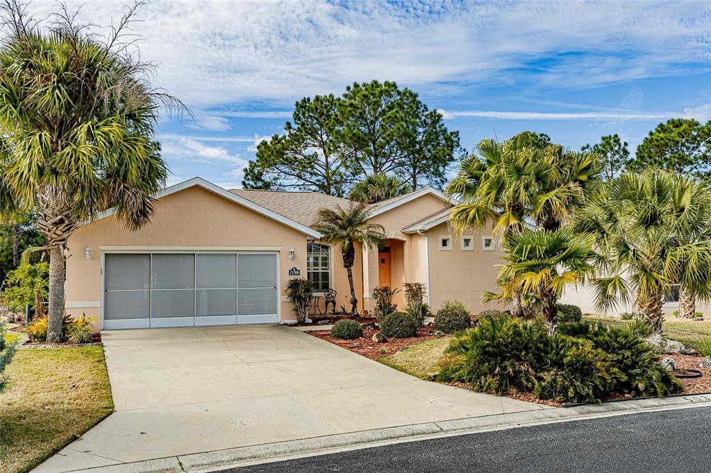 A single-story house with a beige stucco exterior, a concrete driveway, and several palm trees — 15788 SW 11TH TERRACE ROAD, OCALA, FL