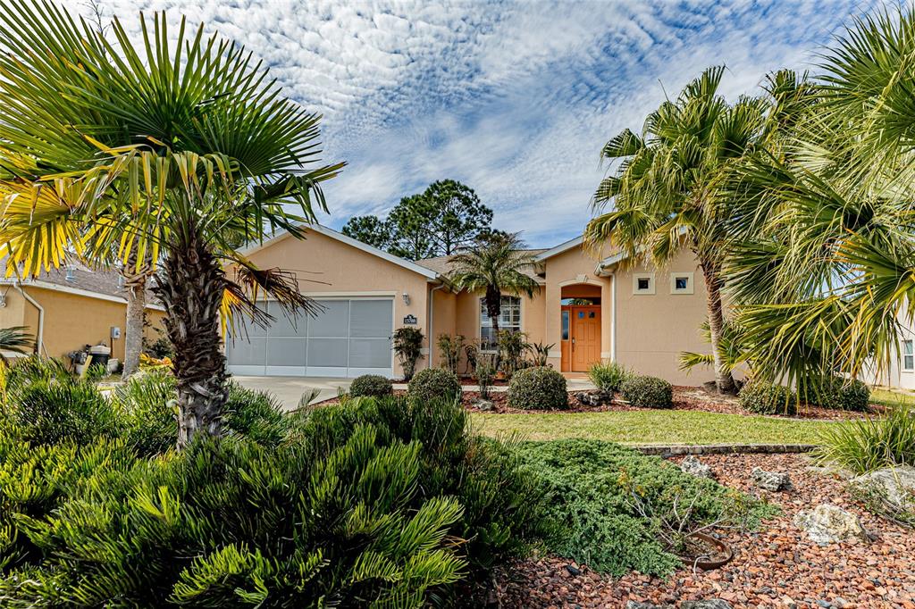 A single-story tan house with a two-car garage and palm trees in the front yard — 15788 SW 11TH TERRACE ROAD, OCALA, FL