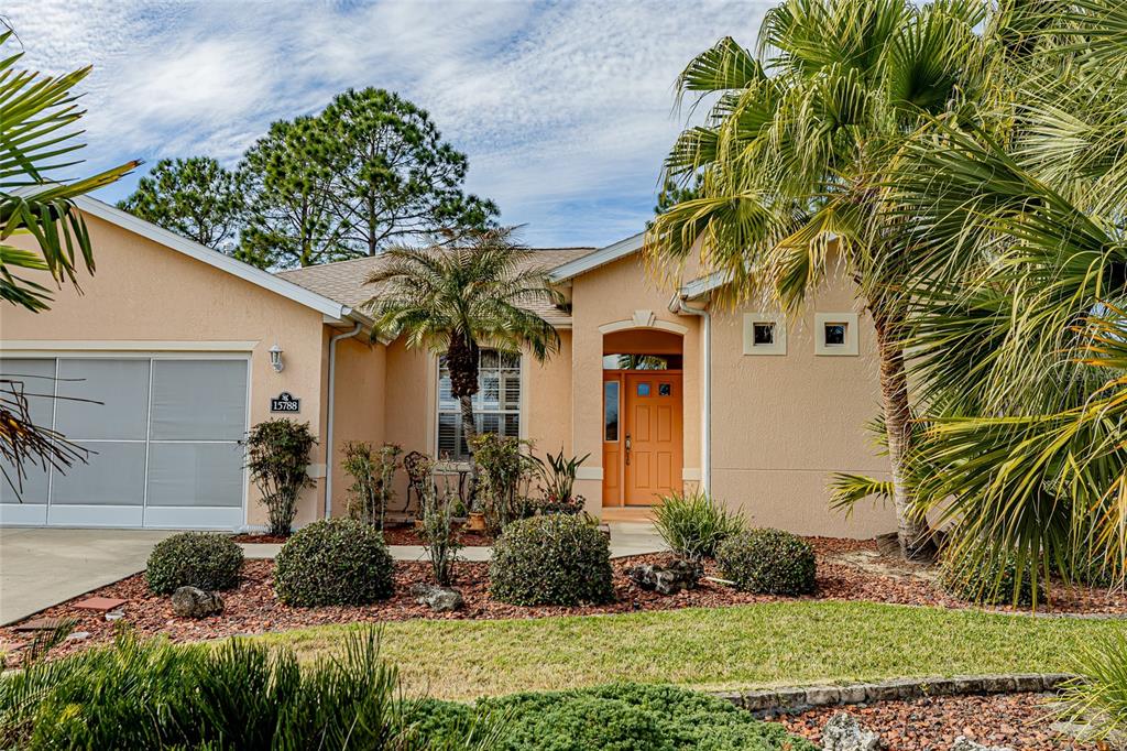 A single-story peach-colored house features a two-car garage, a front entryway, and palm trees — 15788 SW 11TH TERRACE ROAD, OCALA, FL
