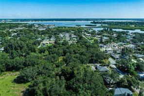 An aerial view shows a wooded lot surrounded by residential homes and a nearby body of water — 2801 11TH AVENUE E, BRADENTON, FL