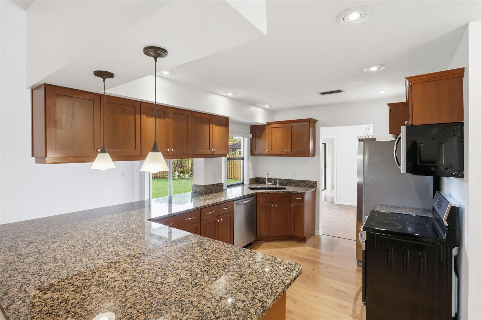 A kitchen features wood cabinets, granite countertops, stainless steel appliances, and a breakfast bar — 7909 NW 18th Place, Margate FL 33063, MARGATE, FL