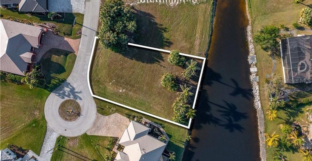 An aerial view shows a vacant, rectangular residential lot bordered by a canal — 16219 CAYMAN LANE, PUNTA GORDA, FL
