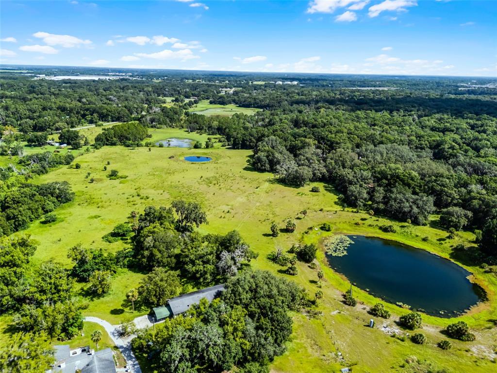 An aerial view shows a rural property with a house, several ponds, and dense forest — 7625 CLARCONA OCOEE ROAD, ORLANDO, FL