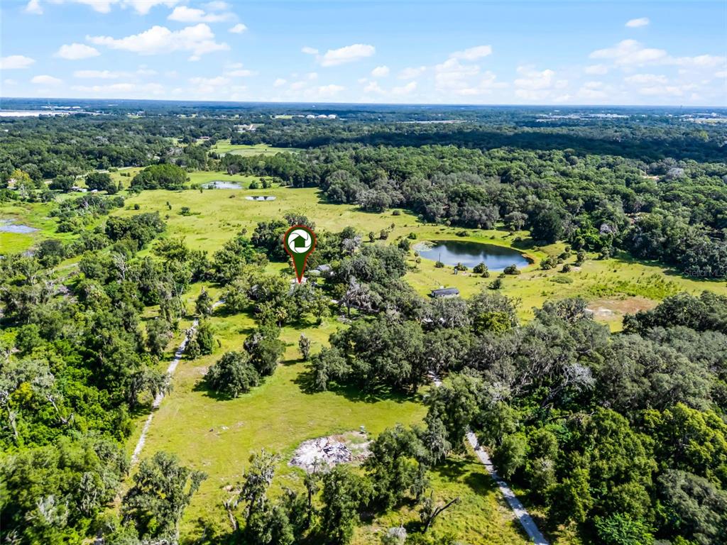 An aerial view shows a rural property with trees, a pond, and a marked house — 7625 CLARCONA OCOEE ROAD, ORLANDO, FL