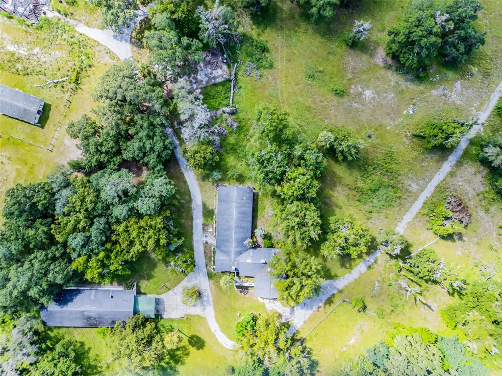Aerial view of a rural property featuring a house, outbuildings, and surrounding trees and fields — 7625 CLARCONA OCOEE ROAD, ORLANDO, FL
