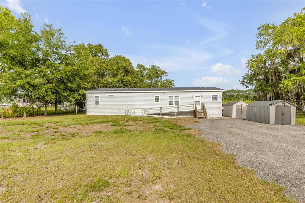 A single-story manufactured home with a wheelchair ramp and two storage sheds in the yard — 640 UNION AVENUE, CRESCENT CITY, FL