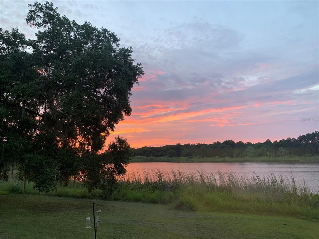 A vibrant sunset glows over a lake with a grassy bank and large oak tree — 640 UNION AVENUE, CRESCENT CITY, FL