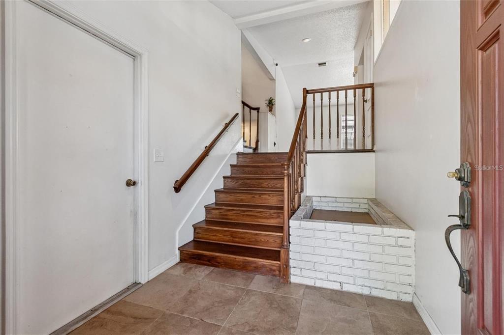 An entryway features a wooden staircase, a white brick planter, and tile flooring — 2620 GIANT PLACE, SEFFNER, FL