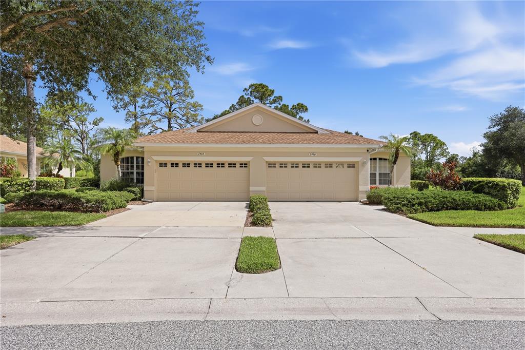 A duplex home with two beige garage doors and a shared concrete driveway — 2462 MAGNOLIA CIRCLE, NORTH PORT, FL