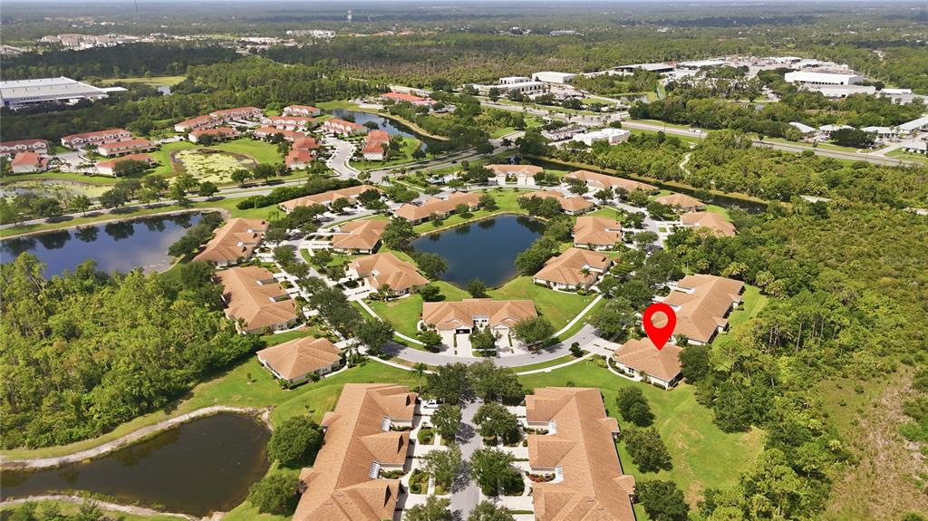 An aerial view shows a residential community with multiple buildings, ponds, and green spaces — 2462 MAGNOLIA CIRCLE, NORTH PORT, FL