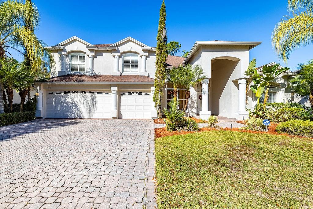 A two-story house with a paved driveway, a three-car garage, and palm trees — 5028 ASHINGTON LANDING DRIVE, TAMPA, FL