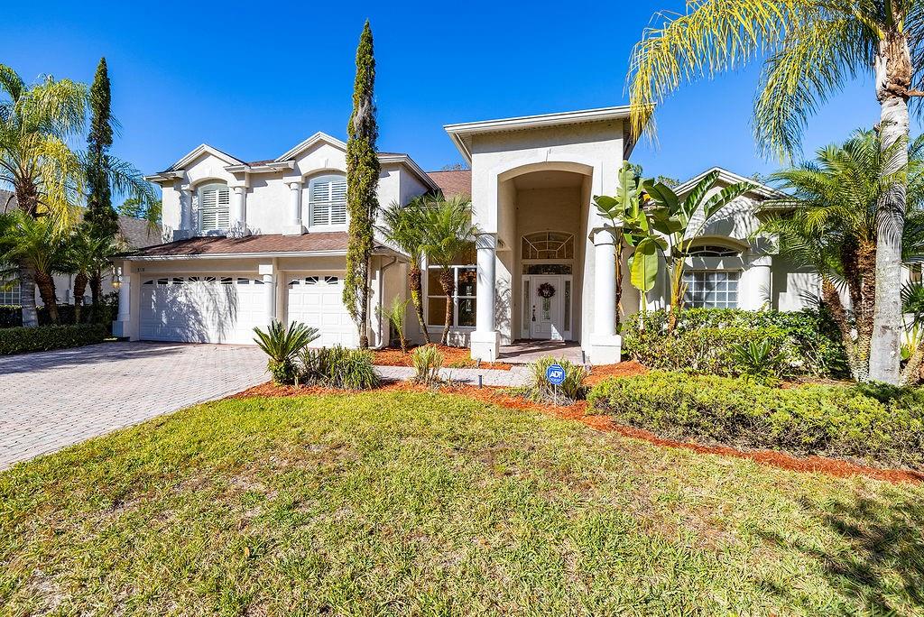 A two-story suburban house with a paved driveway, white garage doors, and palm trees — 5028 ASHINGTON LANDING DRIVE, TAMPA, FL