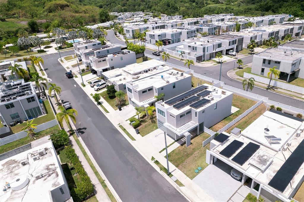 An aerial view shows a residential neighborhood with modern white houses and solar panels — Calle 13 UNIT 134, GUAYNABO, PR