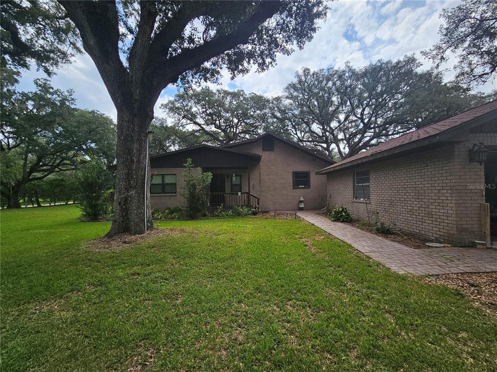 A brick house with a paved walkway and large oak trees in the front yard — 31110 HARTMAN ROAD, SAN ANTONIO, FL