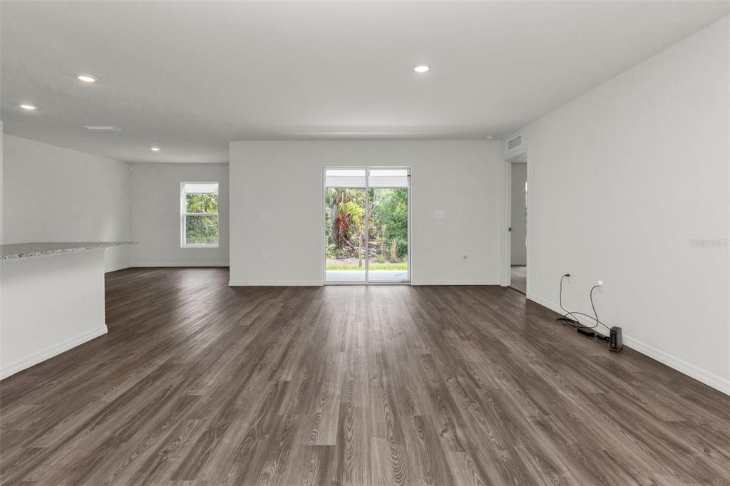 A spacious living area features wood-look flooring, white walls, recessed lighting, and sliding glass doors — 1040 SHERWIN STREET, PORT CHARLOTTE, FL