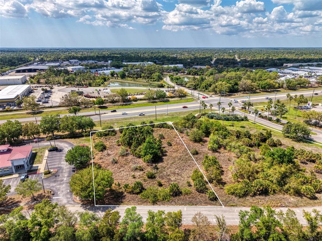 An aerial view shows a vacant, rectangular lot outlined in white next to a parking lot — 2487 SYCAMORE STREET, NORTH PORT, FL