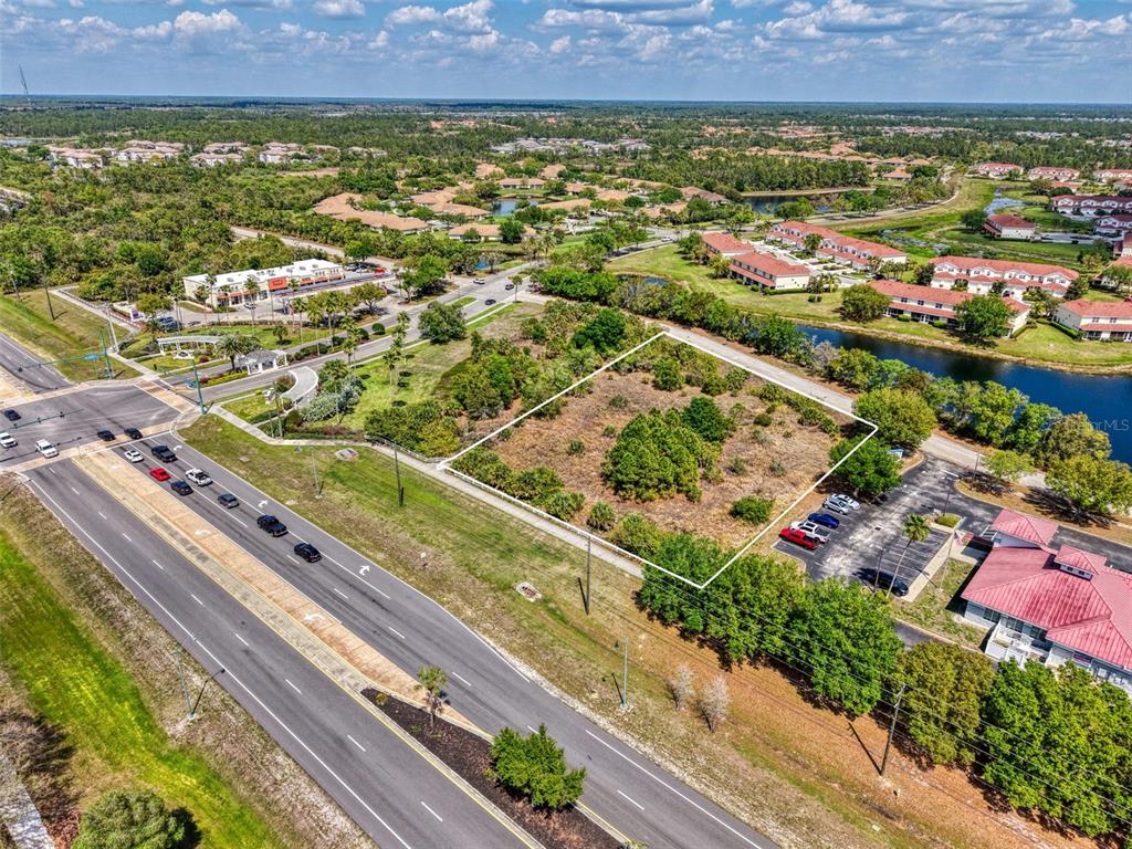 An aerial view shows a vacant, rectangular lot bordered by a road, parking lot, and canal — 2487 SYCAMORE STREET, NORTH PORT, FL
