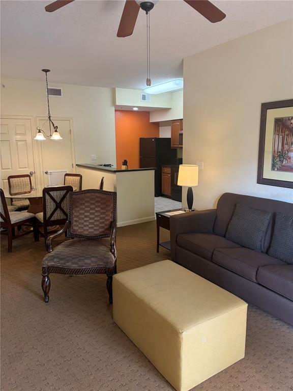 A living room and dining area feature a sofa, ottoman, armchair, and open kitchen — 8101 RESORT VILLAGE DRIVE UNIT 3411, ORLANDO, FL