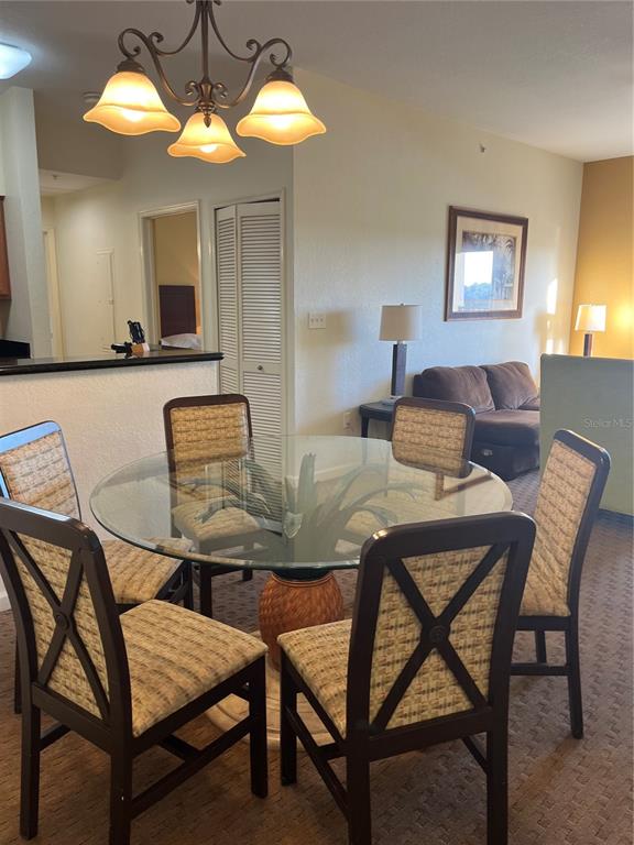 A dining area features a glass-topped table with four chairs under a three-light chandelier — 8101 RESORT VILLAGE DRIVE UNIT 3411, ORLANDO, FL