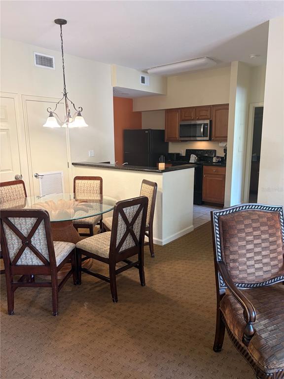 A dining area with a glass table and chairs sits adjacent to a kitchen — 8101 RESORT VILLAGE DRIVE UNIT 3411, ORLANDO, FL