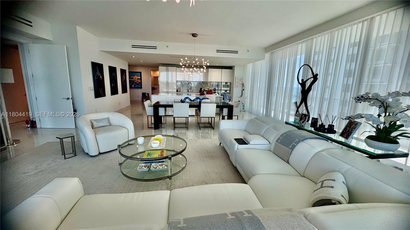 A modern open-concept living and dining area features white leather furniture and marble flooring — 10201 Collins Ave # 511, Bal Harbour FL 33154, BAL HARBOUR, FL